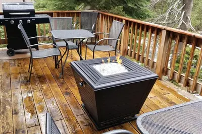 a grill on a deck with chairs and a table at Tamarack Dream in Lakeshore