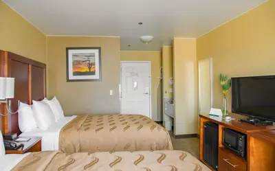 a hotel room with two beds and a flat screen tv at Quality Inn Merced Gateway to Yosemite in Merced