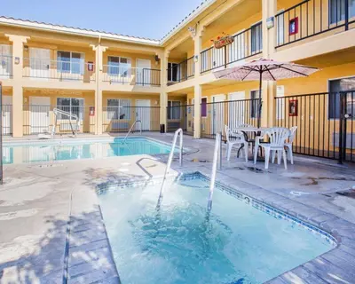 a swimming pool with a table and an umbrella at Econo Lodge Inn & Suites Lodi - Wine Country Area in Lodi