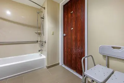 a bathroom with a bath tub and a wooden door at Comfort Suites Visalia - Convention Center in Visalia