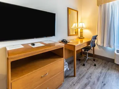 a hotel room with a desk with a large television at The Hanford Hotel, an Ascend Collection Hotel in Hanford