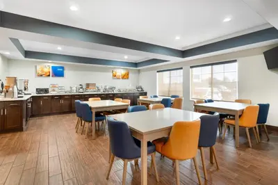 a dining room with tables and chairs and a kitchen at Comfort Inn & Suites Sacramento - University Area in Sacramento