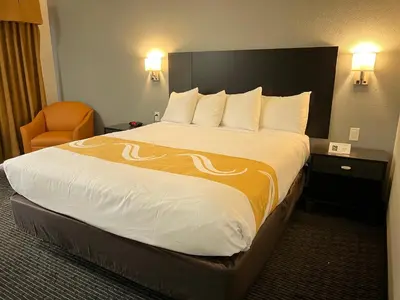 a hotel room with a large bed and a chair at Quality Inn & Suites South San Jose - Morgan Hill in Morgan Hill
