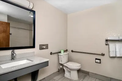 a bathroom with a toilet and a sink and a mirror at Quality Inn & Suites South San Jose - Morgan Hill in Morgan Hill