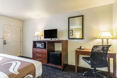 a hotel room with a bed and a desk and a television at Quality Inn Fresno Near University in Fresno