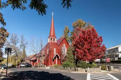 a red church with a steeple on a street at Hotel Lumberjack - Sonora in Sonora
