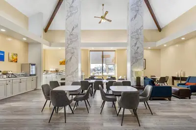 a lobby with tables and chairs and a kitchen at Comfort Inn & Suites Near Fallon Naval Air Station in Fallon