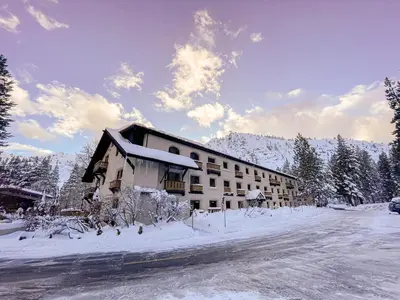 a building with snow on the ground next to a road at Olympic Village Inn Olympic Valley in Olympic Valley