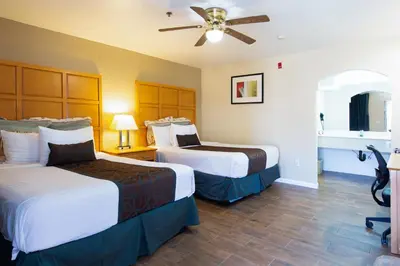 a hotel room with two beds and a ceiling fan at Signature Inn Merced Yosemite Parkway in Merced