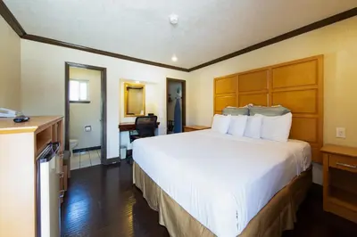 a hotel room with a large bed and a desk at Signature Inn Merced Yosemite Parkway in Merced