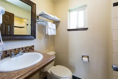 a bathroom with a sink and a toilet and a mirror at Signature Inn Merced Yosemite Parkway in Merced