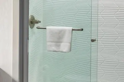 a towel hanging on a shower door in a bathroom at Signature Inn Merced Yosemite Parkway in Merced