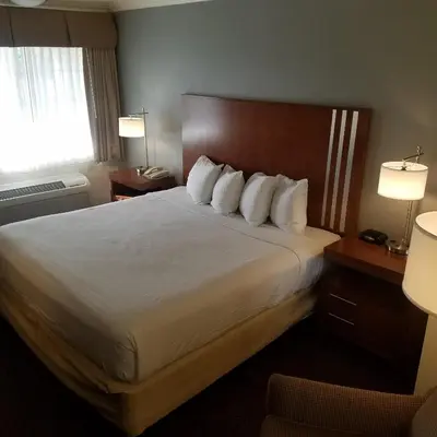 a hotel room with a bed with white sheets and pillows at SureStay Hotel by Best Western Hollister in Hollister