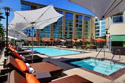 a swimming pool with benches and umbrellas in front of a building at University Plaza Waterfront Hotel in Stockton
