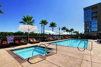 a swimming pool with chairs and umbrellas in a resort at University Plaza Waterfront Hotel in Stockton