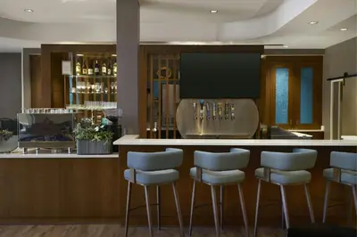 a bar with white stools in a room at Hotel Vista Sierra in Auburn