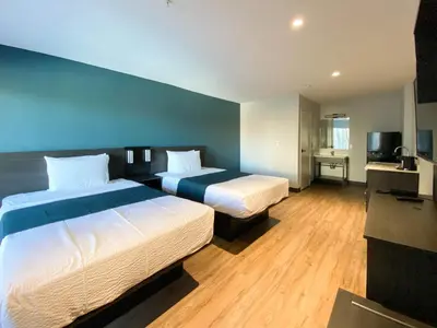 a bedroom with two beds and a blue wall at Studio 6 Suites Stockton, CA Waterfront in Stockton