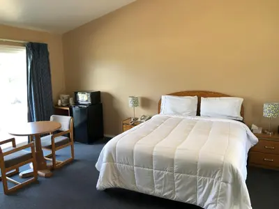 a bedroom with a large bed and a table and a desk at Meadowcliff Lodge Coleville in Coleville