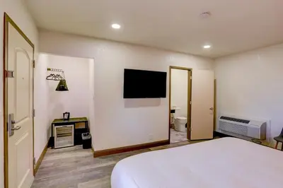 a bedroom with a bed and a tv on the wall at The Greens Hotel on Stockton in Sacramento