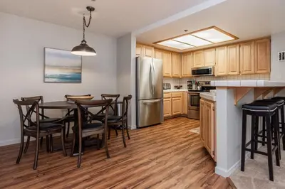 a kitchen with a table and a stainless steel refrigerator at Silver Bear #19 Condo in Mammoth Lakes