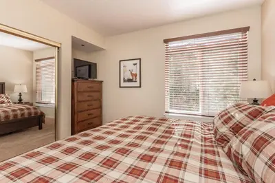 a bedroom with a bed and a dresser and a window at Silver Bear #19 Condo in Mammoth Lakes