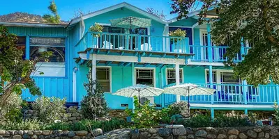 a blue house with umbrellas in front of it at Rio Sierra Riverhouse in Three Rivers
