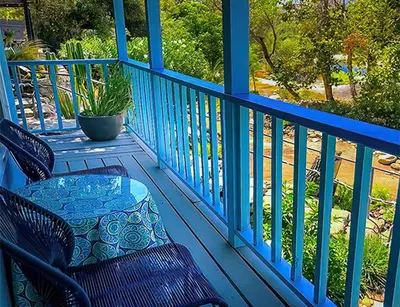 a blue porch with two chairs and a table at Rio Sierra Riverhouse in Three Rivers