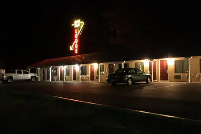 a motel with a car parked in a parking lot at night at Gold Trail Motor Lodge in Placerville