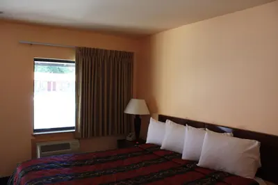 a hotel room with a bed with pillows and a window at Gold Trail Motor Lodge in Placerville