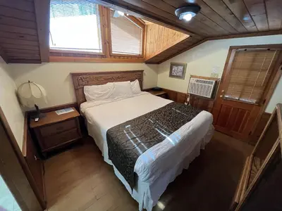 a bedroom with a bed in a room with wooden floors at Whispering Pines Lodge in Kernville