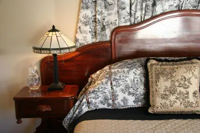 a bed with a wooden headboard and a lamp on a table at Eureka Street Inn in Sutter Creek