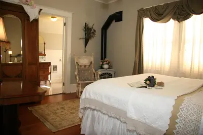 a bedroom with a white bed and a mirror at Eureka Street Inn in Sutter Creek