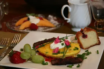 a plate of food with sausage and fruit on a table at Eureka Street Inn in Sutter Creek