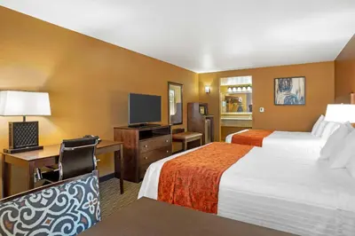 a hotel room with two beds and a desk and a television at Best Western Exeter Inn & Suites in Exeter