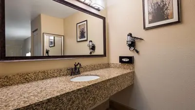 a bathroom with a sink and a large mirror at Best Western Apricot Inn in Chaney Ranch