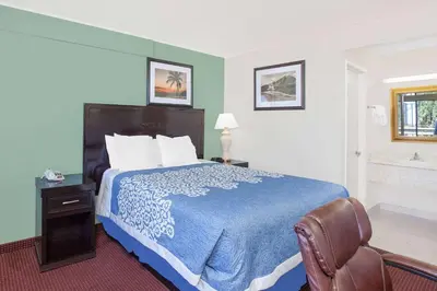a hotel room with a bed and a chair at Days Inn by Wyndham Lost Hills in Lost Hills
