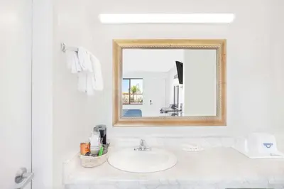 a white bathroom with a sink and a mirror at Days Inn by Wyndham Lost Hills in Lost Hills