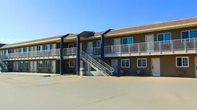 a large building with a staircase in a parking lot at Corcoran Country Inn in Corcoran
