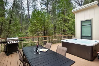 a deck with a table and a hot tub at 11R Spring Meadow Retreat in Wawona