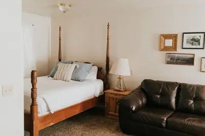 a bedroom with a bed and a leather couch at The Long Barn Lodge in Long Barn