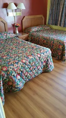 a hotel room with two beds with a flowered bed spread at Slumber Motel in Merced