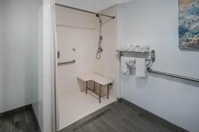 a white bathroom with a shower and a stool at Days Inn by Wyndham Galt - Elk Grove South in Galt