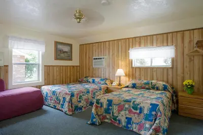two beds in a room with wood paneled walls at Lazy J Ranch Motel in Three Rivers