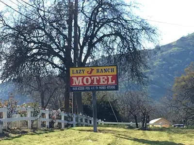 a sign for a motel next to a white fence at Lazy J Ranch Motel in Three Rivers