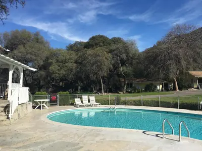 a swimming pool with two chairs and a fence at Lazy J Ranch Motel in Three Rivers