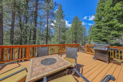 a wooden deck with a grill and a table and chairs at Montgomery Estates Retreat in South Lake Tahoe