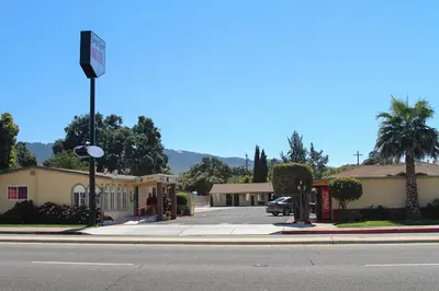 a street sign in front of a building with a parking lot at King's Rest Motel in Gilroy