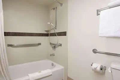 a bathroom with a white tub and a toilet at Days Inn & Suites by Wyndham Rancho Cordova in Rancho Cordova
