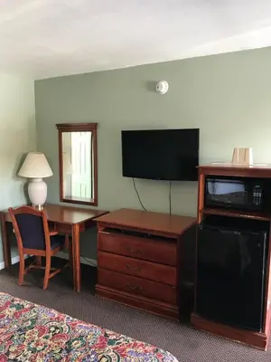 a hotel room with a desk and a flat screen tv at Economy Inn in Modesto