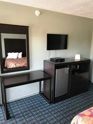 a hotel room with a bed and a flat screen tv at Economy Inn in Modesto